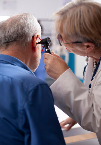 Physician inspects ear of elderly man